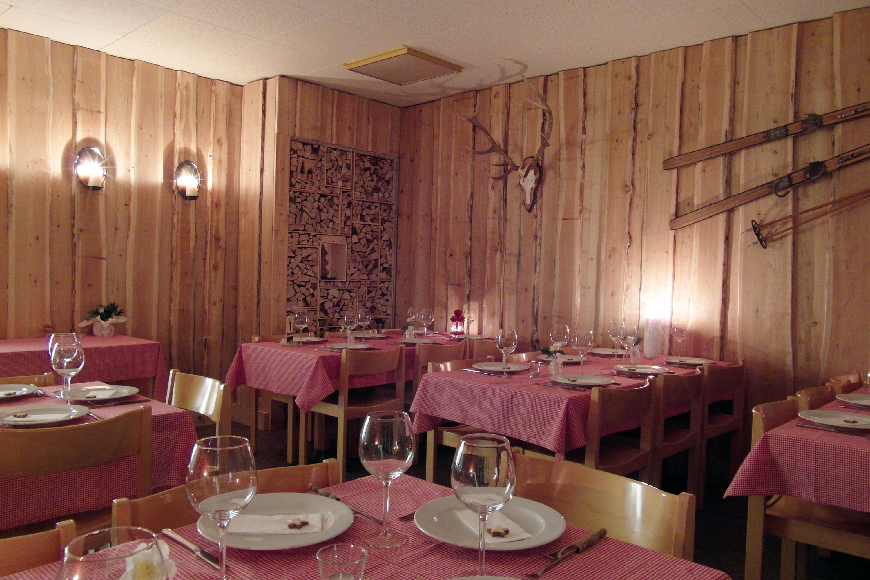 En restaurang med träpanel på väggarna, rödrutiga bordsdukar och ett rådjursskelett som hänger på väggen.