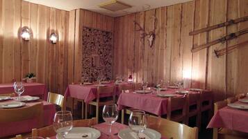 En restaurang med träpanel på väggarna, rödrutiga bordsdukar och ett rådjursskelett som hänger på väggen.