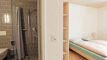 A bathroom with a shower, toilet, and a bed with a wooden headboard.
