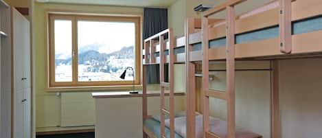 Habitación con literas, un escritorio y ventana con vistas a un paisaje nevado.