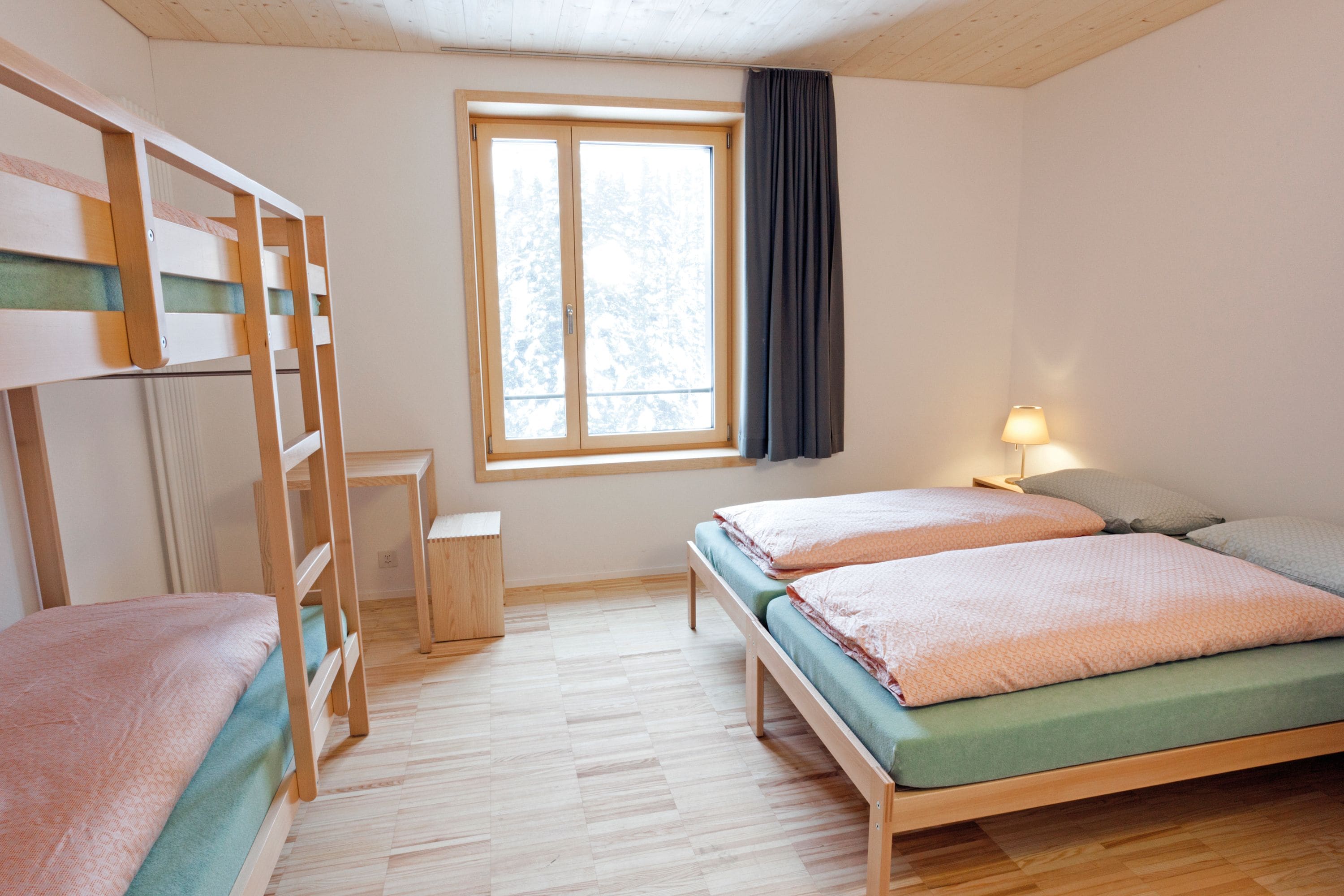 Una habitación con dos literas, un escritorio, una ventana con cortinas y una lámpara.