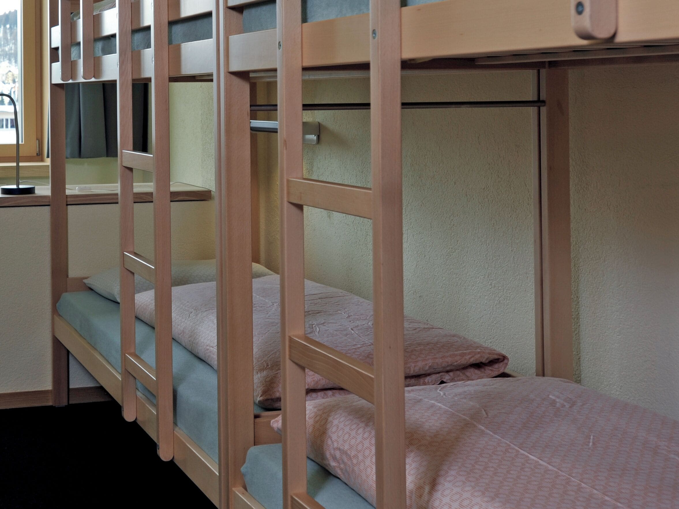A bunk bed room with a window, a desk, and a chair.