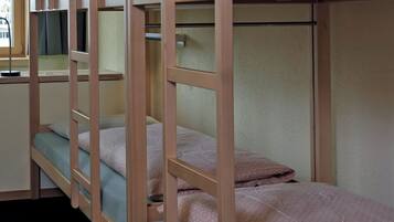 A bunk bed room with a window, a desk, and a chair.