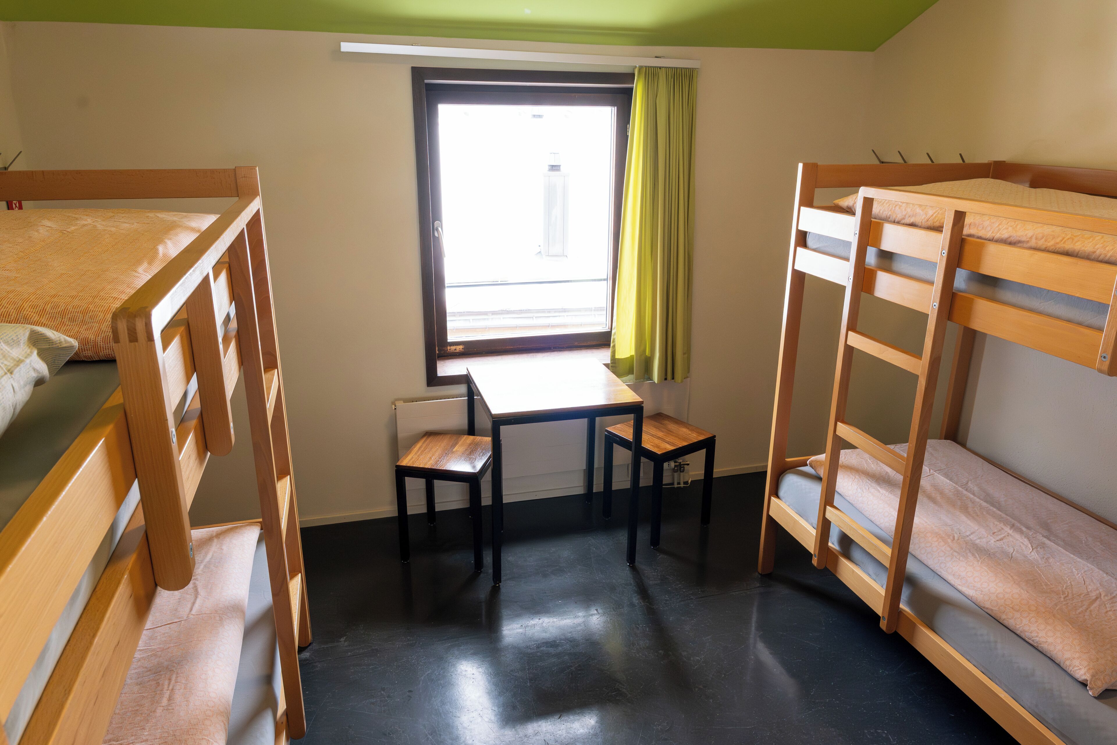 Un dormitorio con literas, un escritorio y una ventana con cortinas.