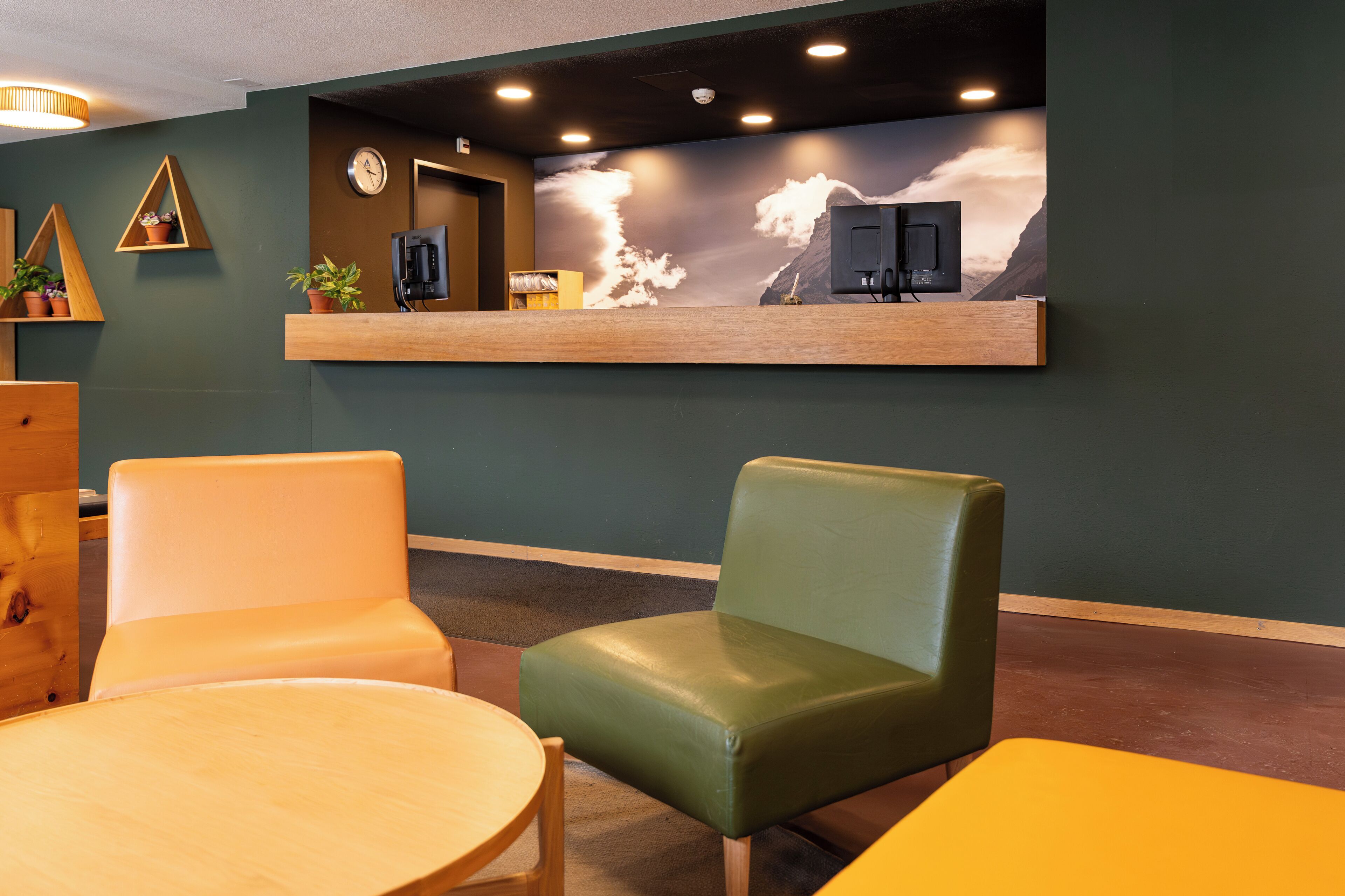 Un espace d’accueil avec un comptoir en bois, une horloge et un téléviseur fixé au mur.