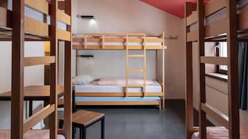 A bunk bed room with a small table and a window.