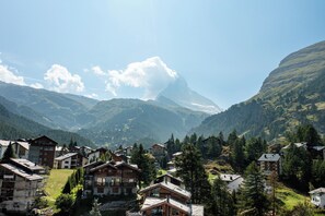 Un village de montagne aux maisons traditionnelles en bois, dominé par un sommet imposant et entouré d’une végétation luxuriante.