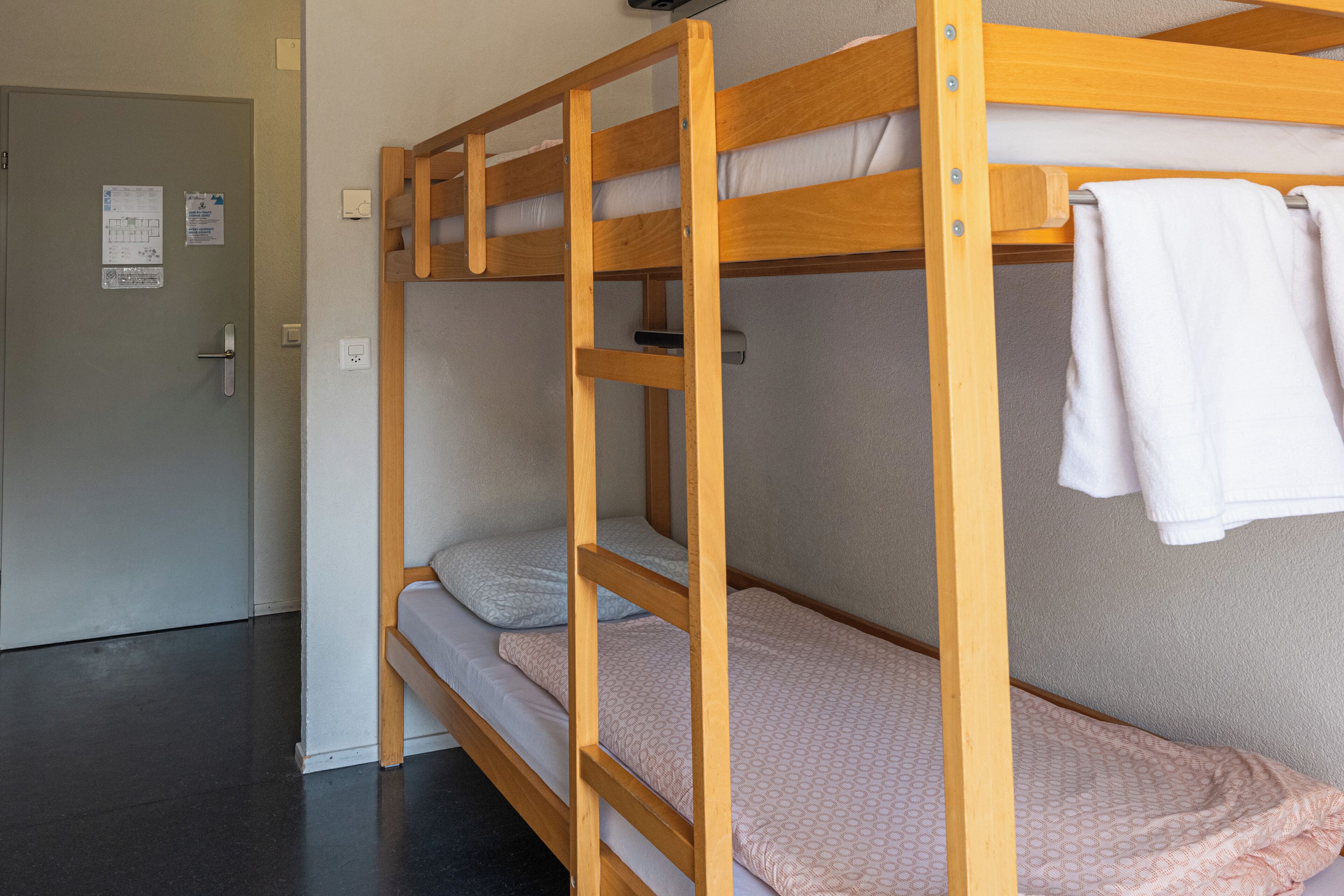 A bunk bed with a ladder, a door with a handle, and a towel hanging on the side.