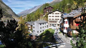 Une ville de montagne qui se distingue par un bâtiment imposant doté de nombreux balcons et par la présence d’un télésiège bien visible.