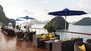 Una terraza con mobiliario de mimbre, sombrillas azules y vistas al mar y a las islas.