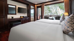 Habitación de hotel con dos camas, un televisor de pantalla plana, un escritorio con computadora y una ventana con vistas a un paisaje montañoso.