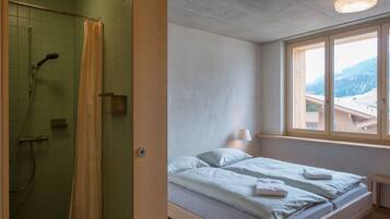 Un dormitorio con cama, ventana con vistas y zona de ducha.