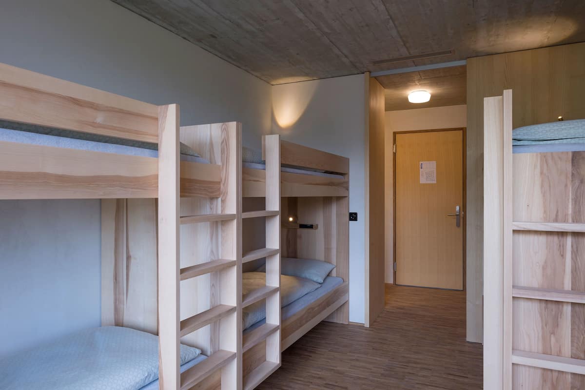 A bunk bed room with a wooden floor and a door in the background.