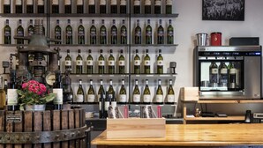 Una bodega con numerosas botellas en estanterías, un barril de madera y un enfriador de vino.