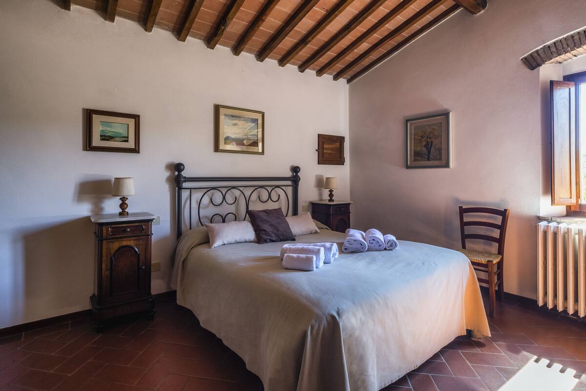 Une chambre à coucher bien rangée, avec un lit, des tables de chevet et une chaise.
