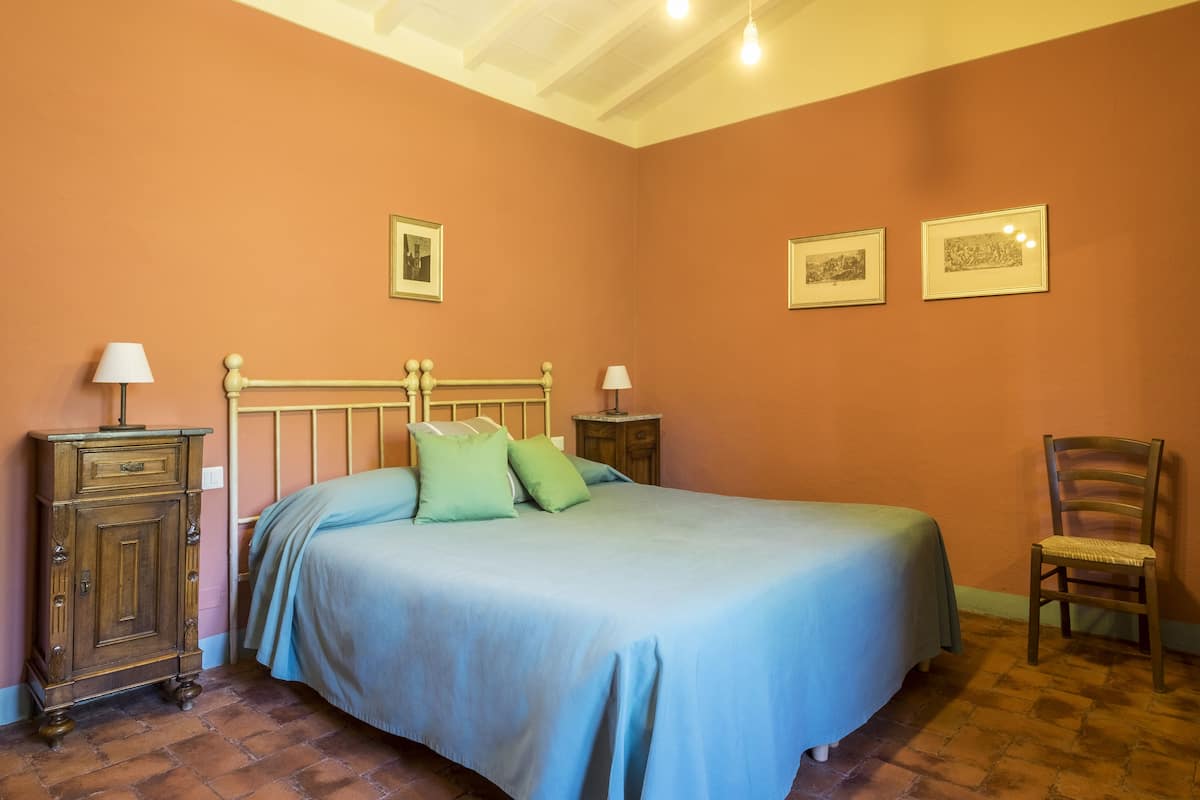 Une chambre à coucher comprenant un lit, deux tables de chevet, une chaise et une armoire.