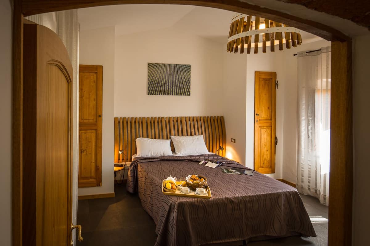 Une chambre d’hôtel avec un grand lit, une tête de lit en bois et un plateau contenant divers articles pour le petit-déjeuner.