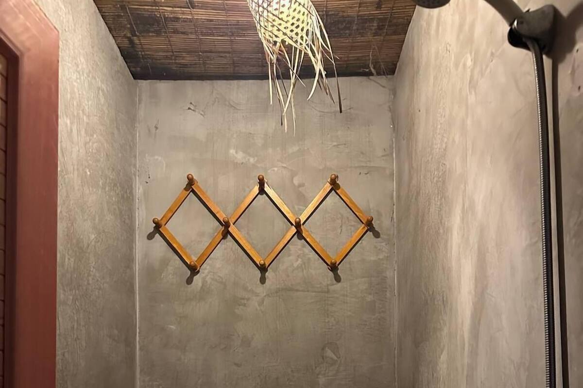 A small bathroom with a toilet, a shower, and a shelf with toiletries.
