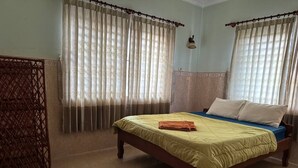 Une chambre à coucher avec un lit, des rideaux et une armoire en bois.
