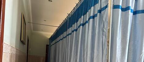 Een hotelgang met blauw-witte gestreepte gordijnen, een houten constructie en een betegelde vloer.