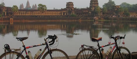 A view of Angkor Wat temple complex with two bicycles parked by the water.