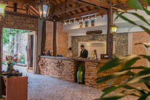 A reception area with a wooden counter, a receptionist, and a guest.