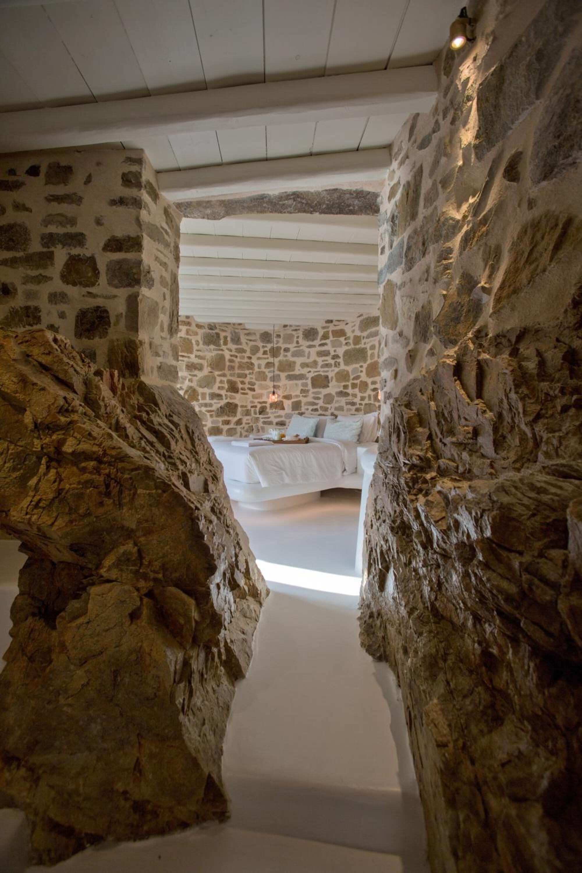 A stone-walled bedroom with a bed and a nightstand.