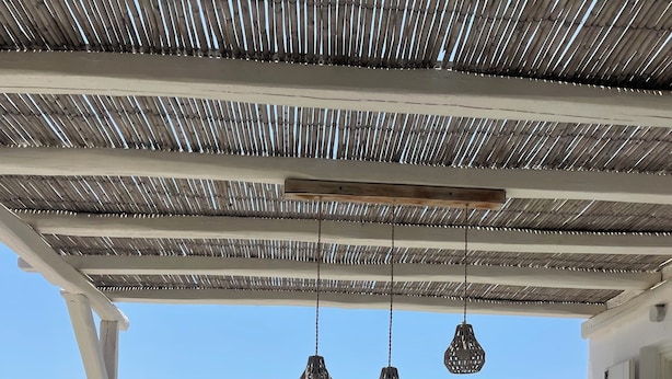 A covered outdoor seating area with a view of the sea. - Salty Houses (Mykonos)