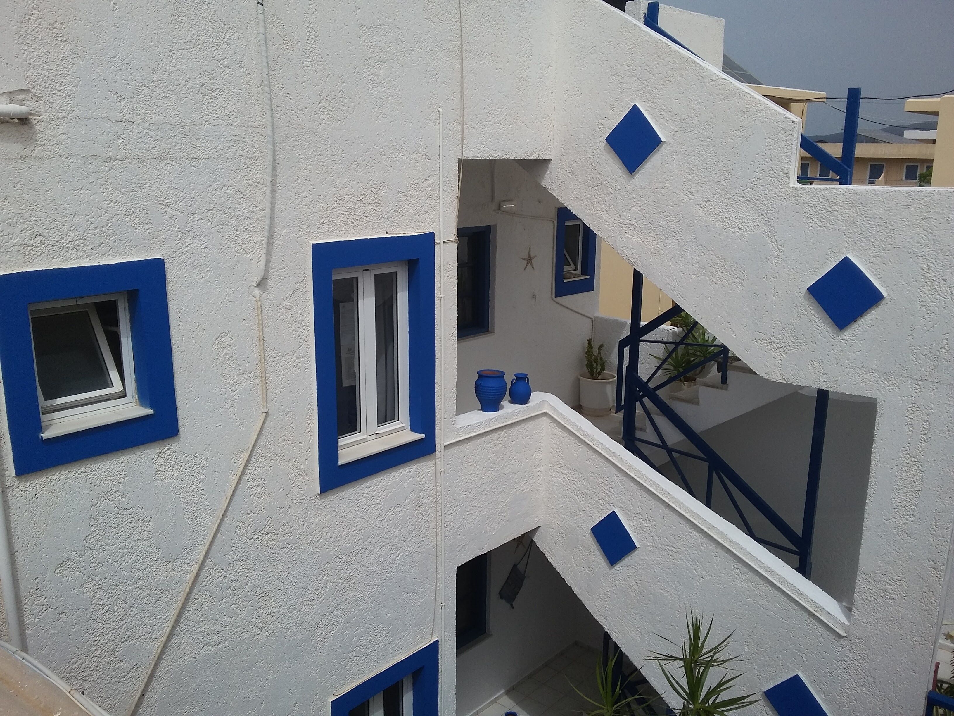 Un edificio a più livelli con finestre a telaio blu e pareti bianche.
