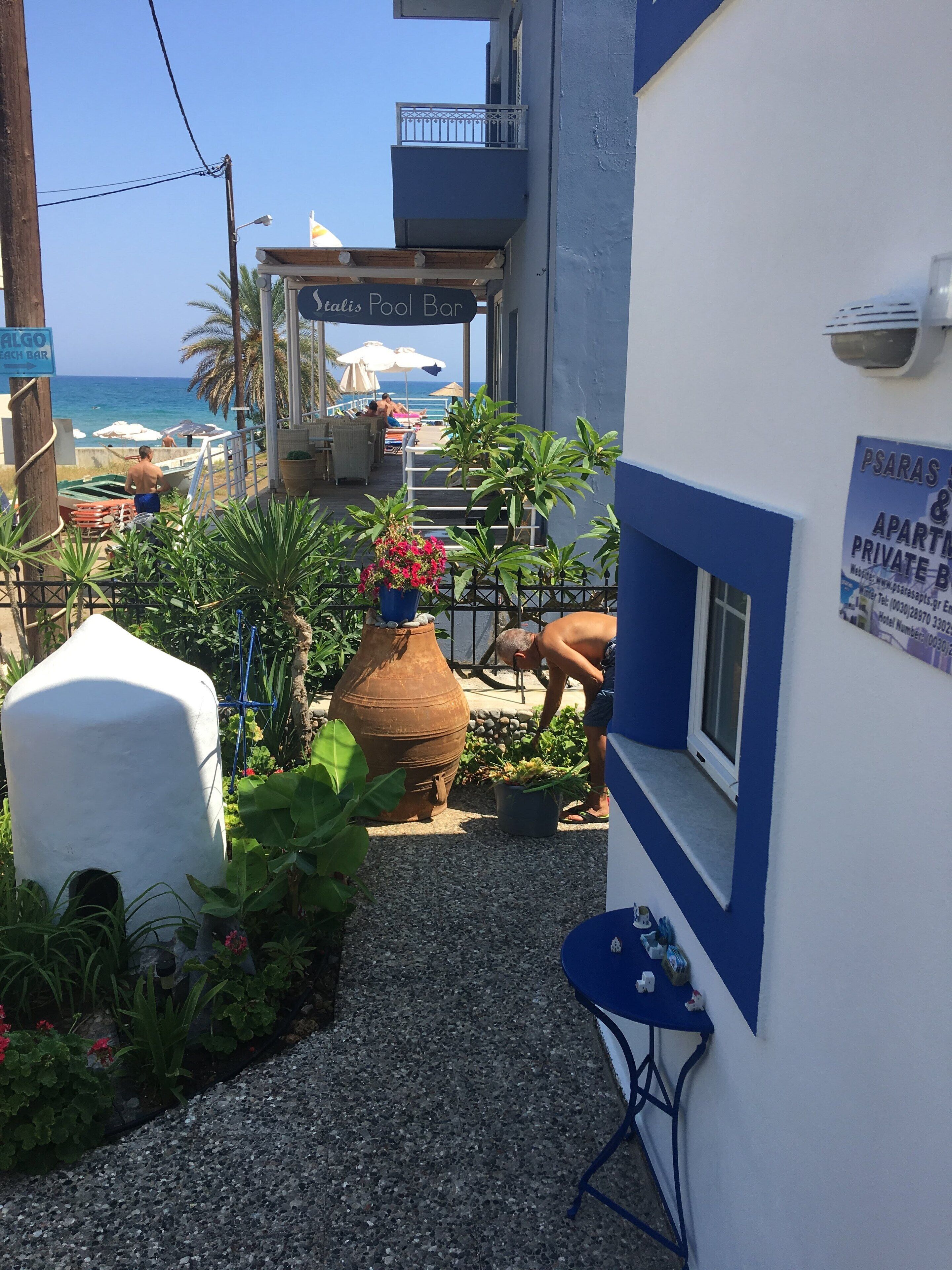 Ein schmaler Gang mit einer Poolbar namens 'Stalisi Pool Bar' und einem Schild für 'PSARAS & APARTMENTS PRIVATE B'.