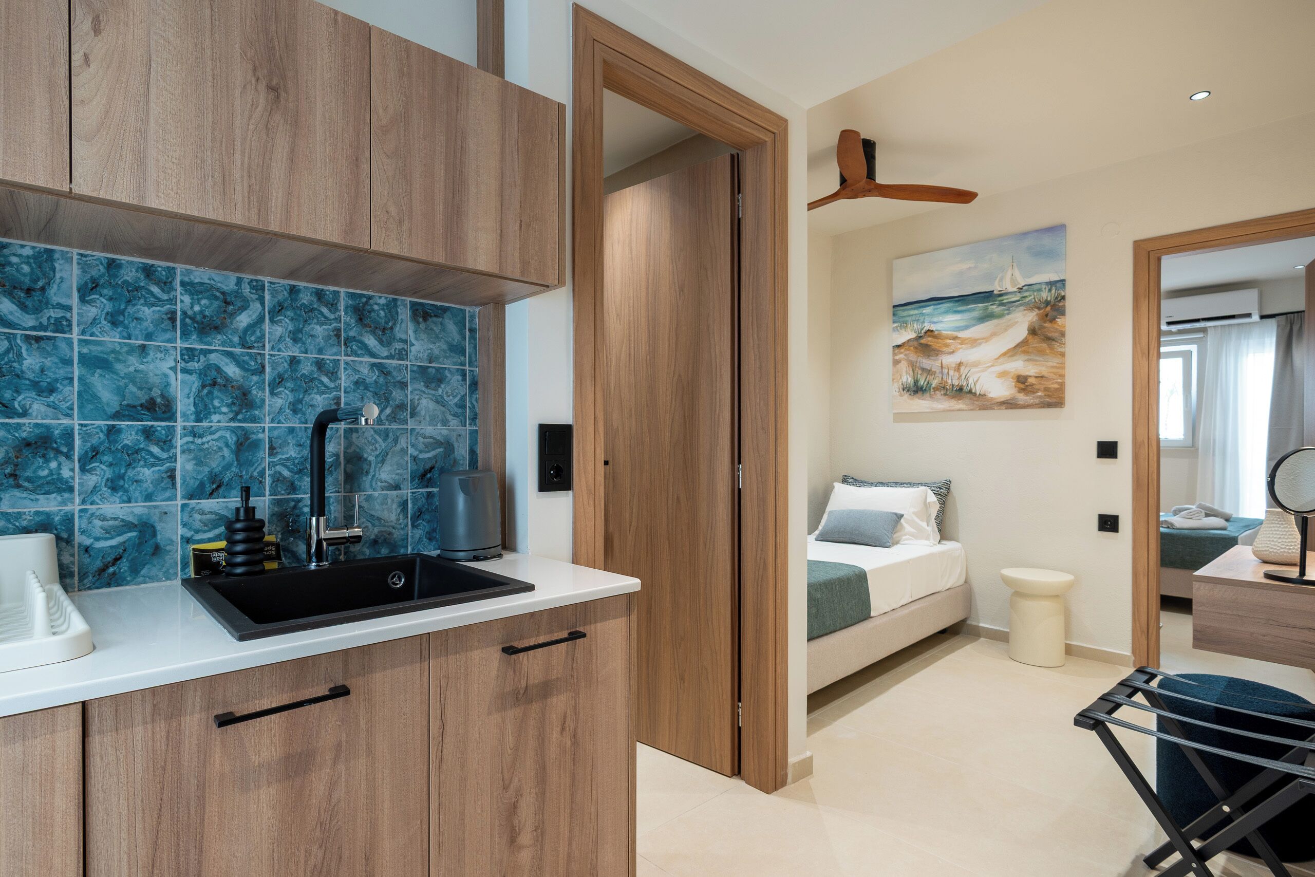 A modern kitchen with wooden cabinets, a black sink, and a blue marble backsplash.