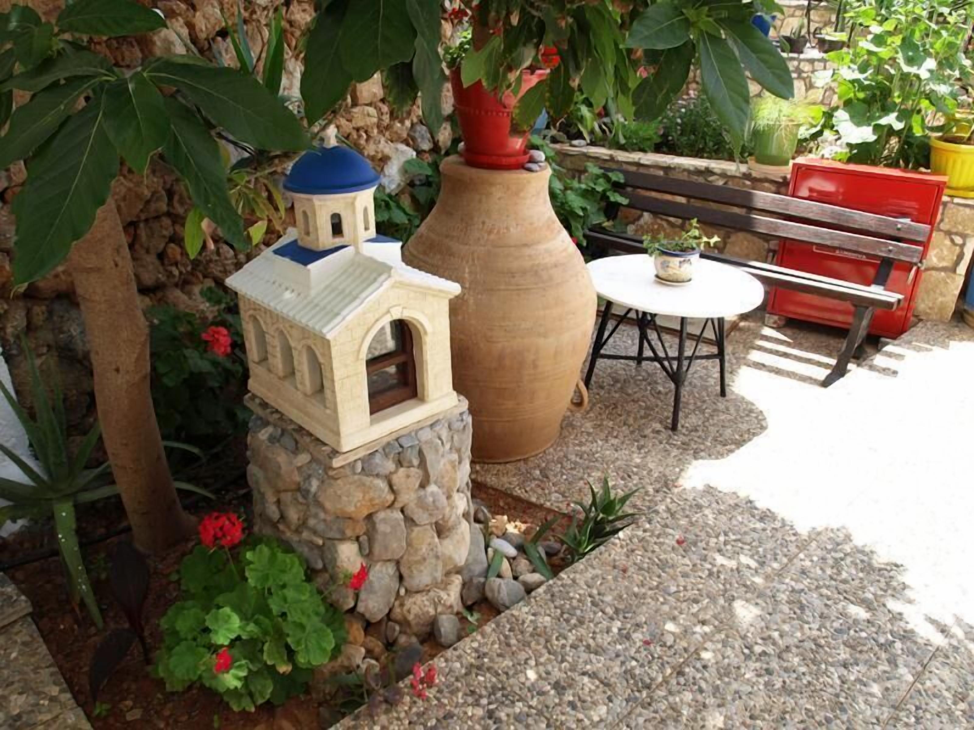 A garden with a stone structure, a large vase, and a bench.