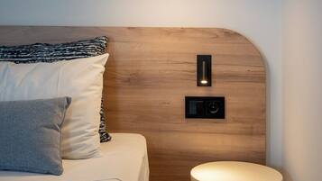 Un dormitorio moderno con cabecera de madera, una mesita de noche, una lámpara colgante e interruptor en la pared.