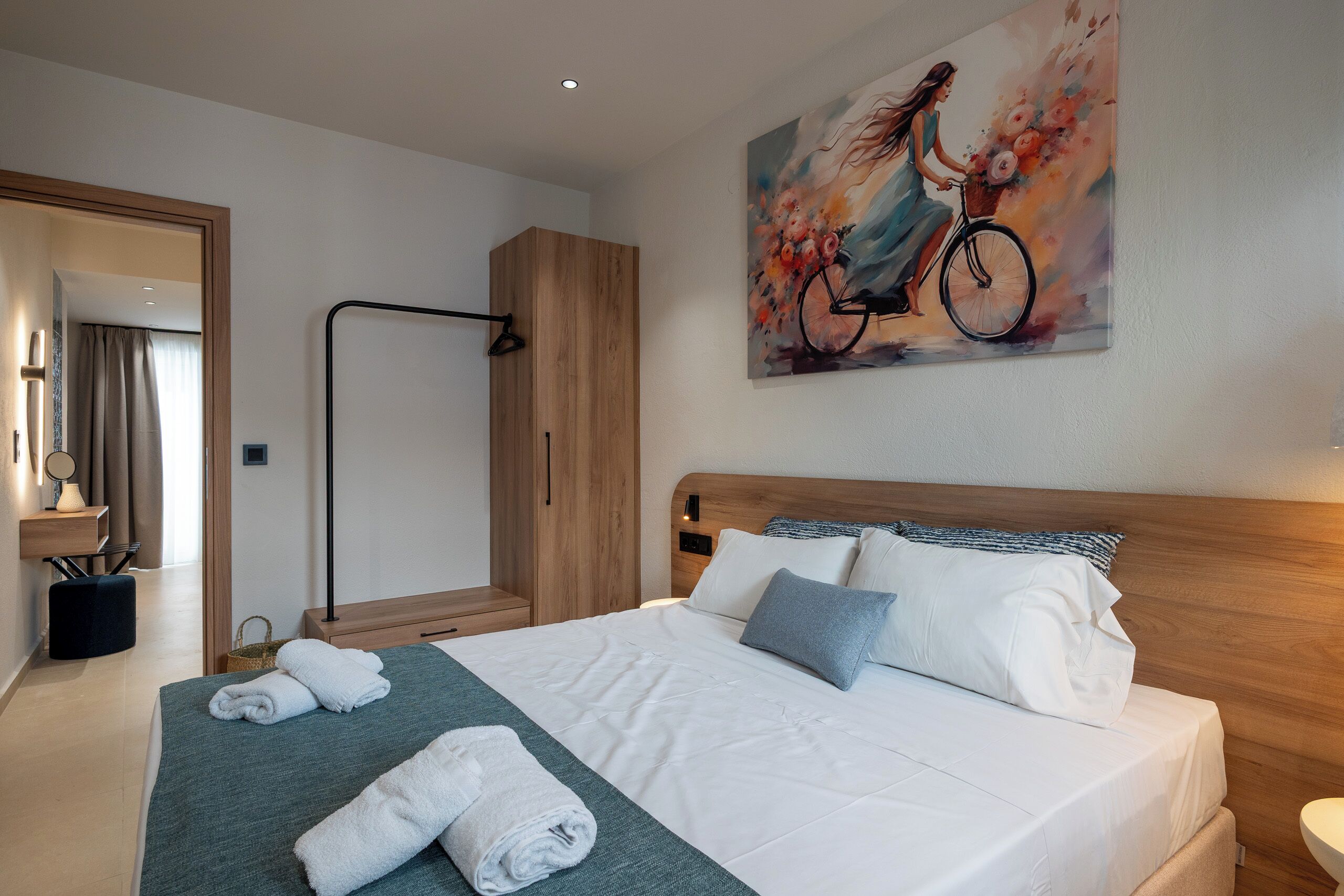 Une chambre d’hôtel avec un lit, des serviettes, un tableau et une armoire en bois.