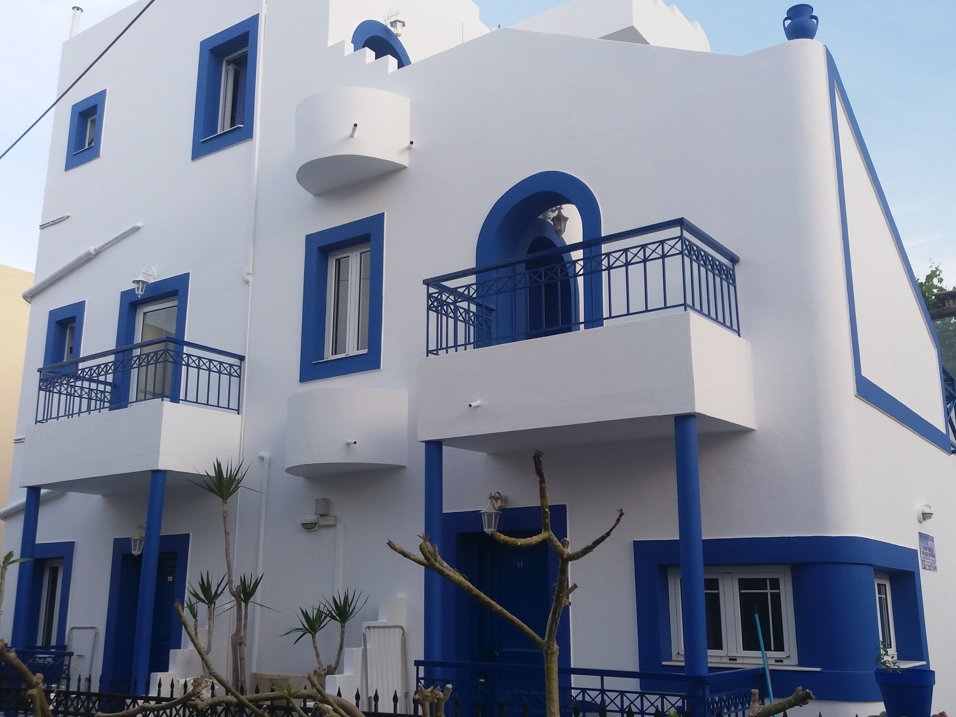 A modern building with multiple balconies, white walls, and blue accents.
