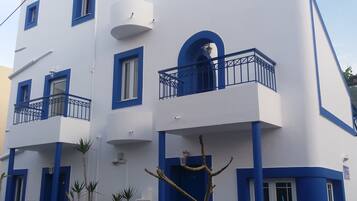 A modern building with multiple balconies, white walls, and blue accents.