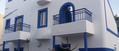 A modern building with multiple balconies, white walls, and blue accents.
