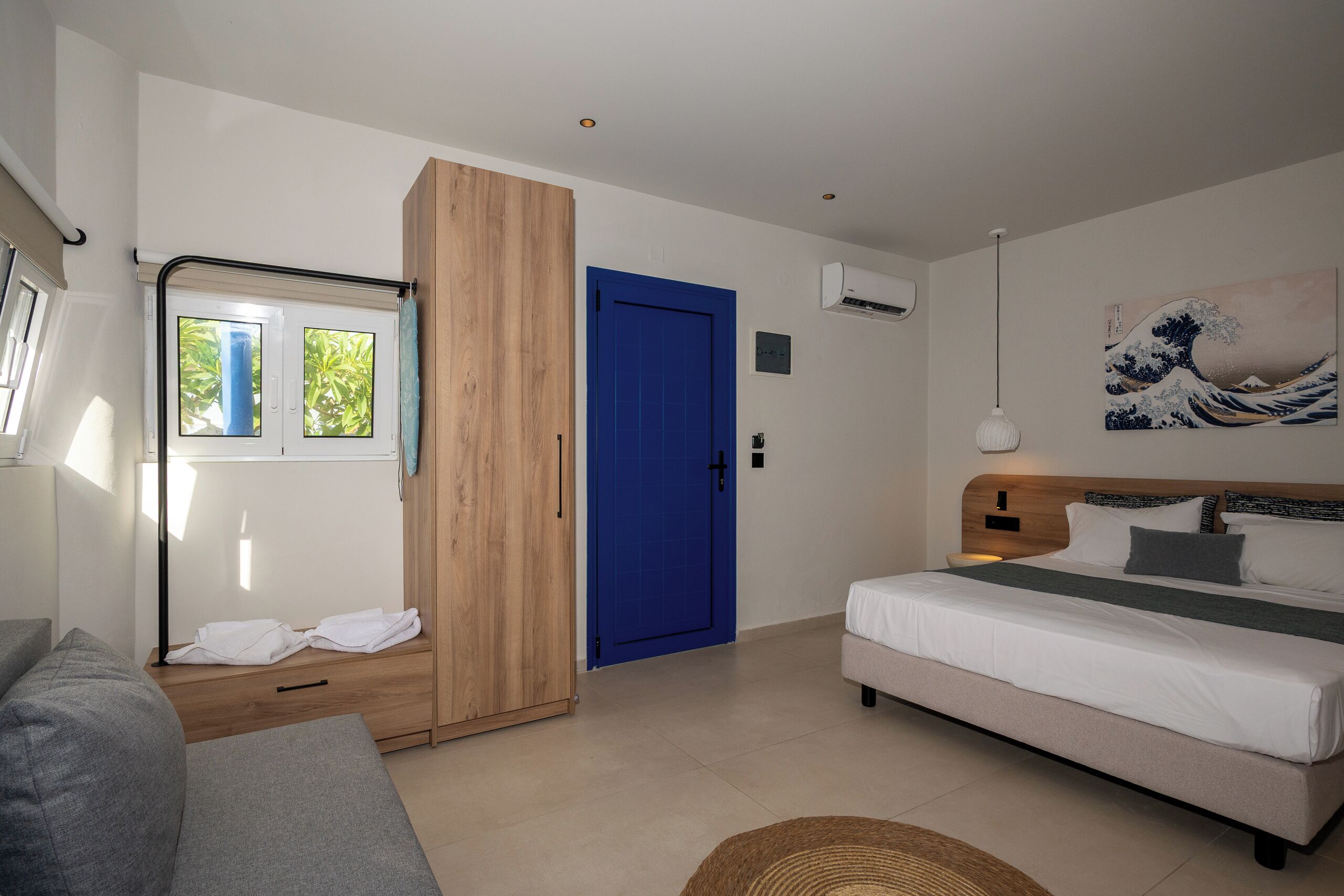 A bedroom with a bed, a wardrobe, a blue door, and a window with curtains.