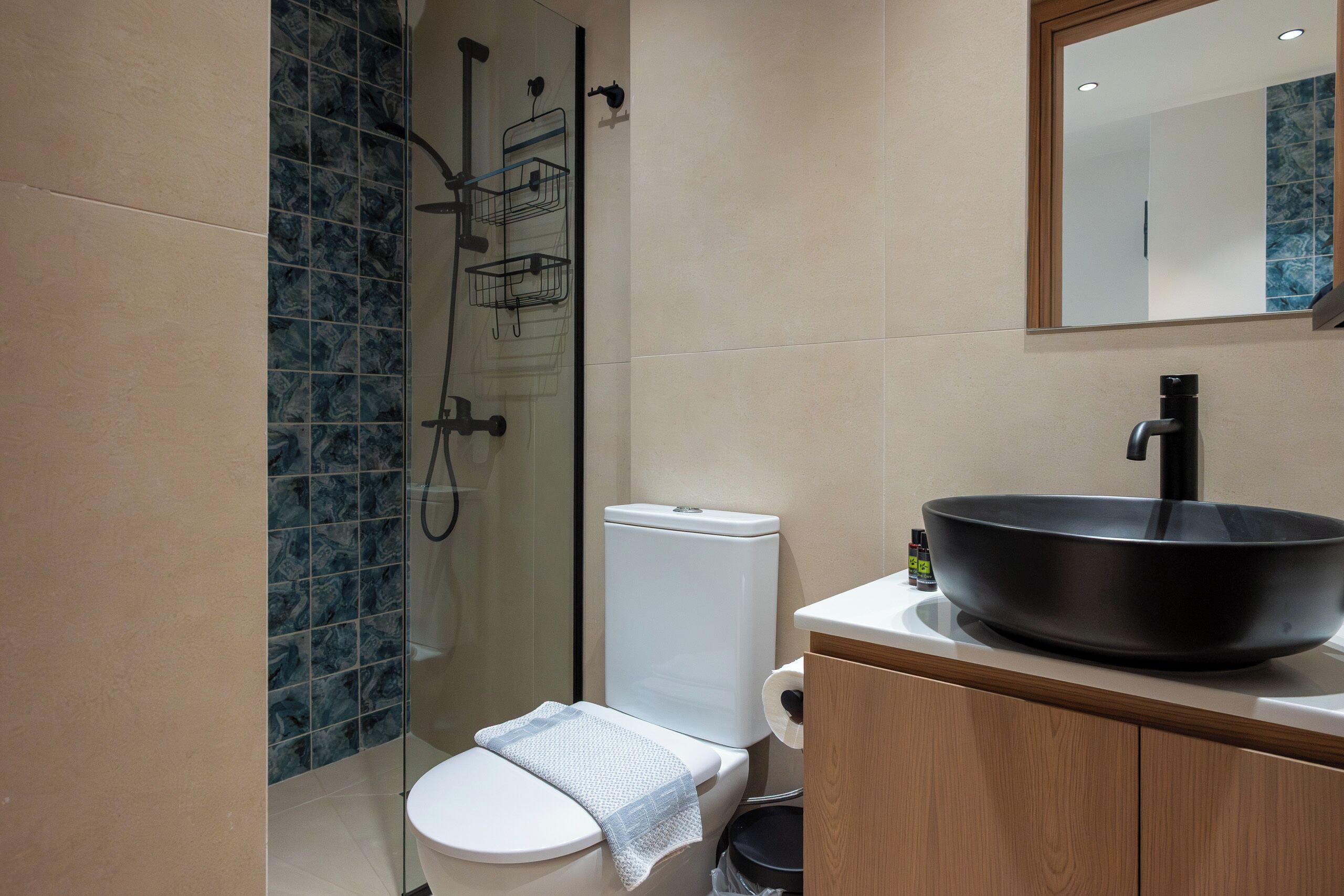 A modern bathroom with a toilet, bidet, and a large black sink.