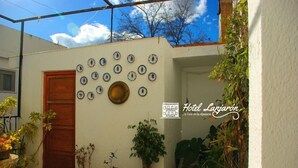 A courtyard with a wooden door, potted plants, and a wall decorated with ceramic plates. - Hotel Lanjarón (Lanjaron)