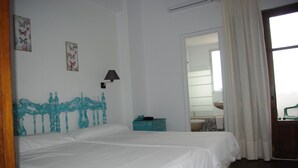 A room with two beds, a wooden headboard, a small table, a lamp, and a bathroom visible through an open door. - Hotel Lanjarón (Lanjaron)