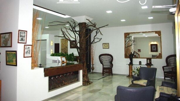 A reception area with a wooden reception desk, a large mirror, and framed artwork on the walls. - Hotel Lanjarón (Lanjaron)