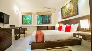 A modern hotel room with a large bed, a desk, a television, and a painting on the wall. - Villa Escondite (Sri Jayawardenepura Kotte)