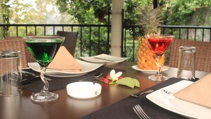 A table set for two with a green cocktail glass, a red cocktail glass with a pineapple, and a white ashtray. - Villa Escondite (Sri Jayawardenepura Kotte)