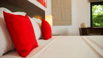 A neatly made bed with red and white pillows, a headboard, and a bedside table with a lamp.