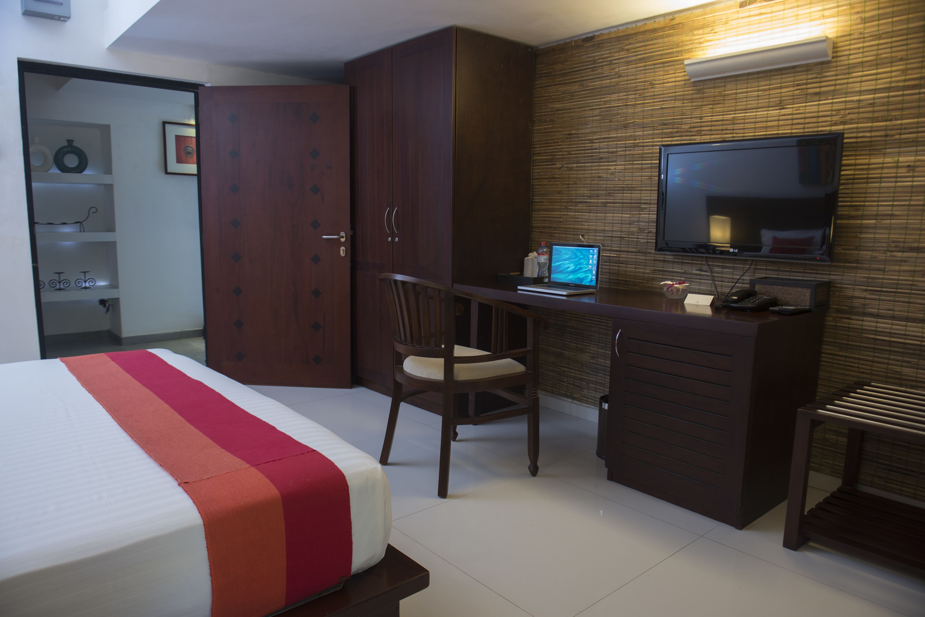 A hotel room with a bed, a desk with a laptop, a TV, and a wardrobe.