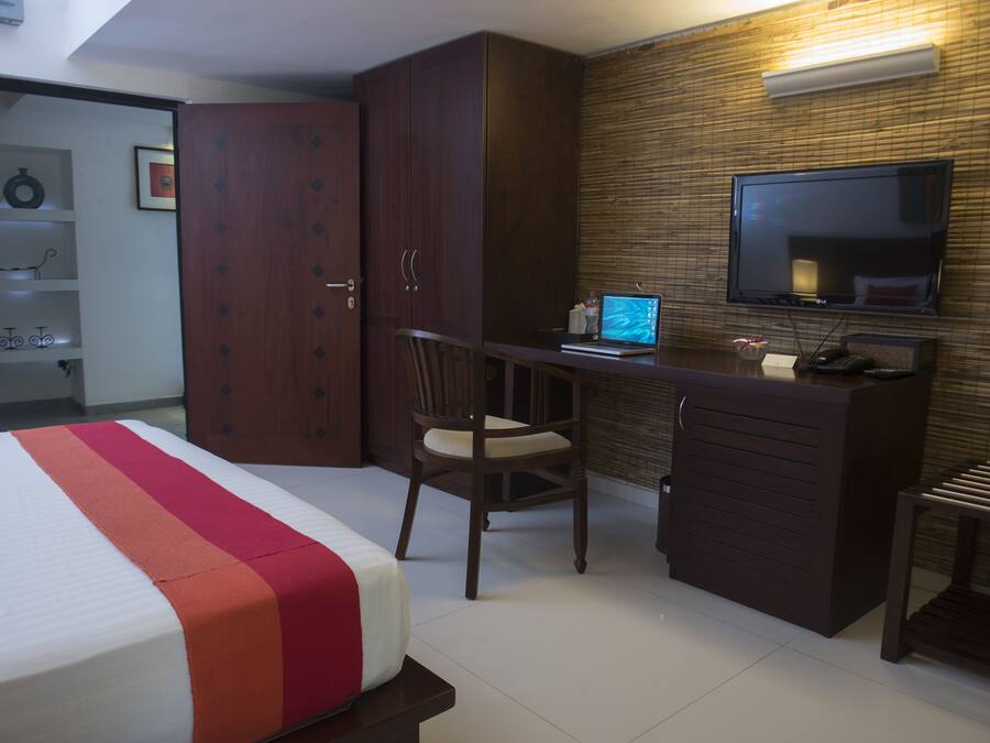 A hotel room with a bed, a desk with a laptop, a TV, and a wardrobe.