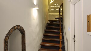 Un escalier avec une rampe en bois et un luminaire fixé au mur.