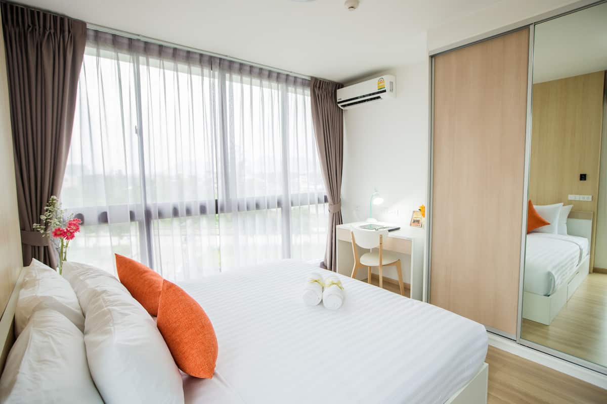 Quarto de hotel com cama grande, escrivaninha e espelho.