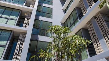 Edifici modern de diverses plantes amb balcons, grans finestres i un cel blau clar.
